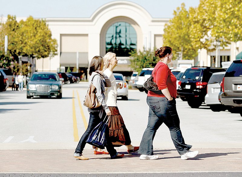 Lacy Dahl of Oklahoma City (from left) and Rhonda King and Diana Huss, both of Siloam Springs, cross the street to other stores while shopping Thursday at the Pinnacle Hills Promenade in Rogers.