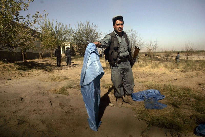 Afghan policeman holds up a burqa worn by one of the attackers outside a UN compound in Herat, west of Kabul, Afghanistan, Saturday, Oct. 23, 2010. A suicide car bomber and three armed militants wearing explosives vests and burqas attacked a United Nations compound Saturday in western Afghanistan, but Afghan security forces killed the attackers and no U.N. employees were harmed, officials said. 