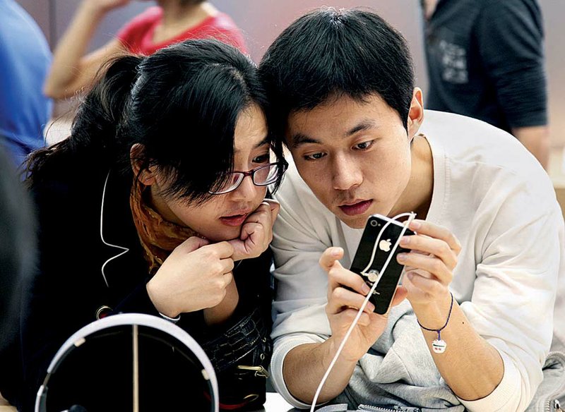 Customers try the iPhone 4 earlier this month in the Apple Store at The Village at Sanlitun shopping center in Beijing.