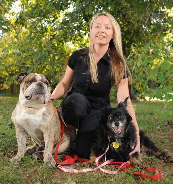 Stephanie Conway of Fayetteville, animal shelter volunteer, holds her dogs, Jake, left, and Daisy Thursday at her home. Conway has been the driving force behind a new program at the shelter placing potential therapy dogs into foster care where they are trained.
