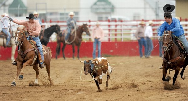 Lucas Sheets of Siloam Springs High School, left, and Brett Jones of Fayetteville High School take part in the team roping competition during the Arkansas High School Rodeo Association’s event Saturday in Parsons Stadium in Springdale. Jones and Sheets received a no time in the event.