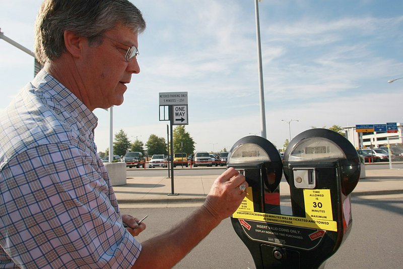 This October 24, 2010 file photo shows Stuart Oden of Shreveport feeding a meter at Little Rock National Airport. The Little Rock Municipal Airport Commission voted Tuesday to establish a trial cell phone lot at the Aerospace Education Center property.
