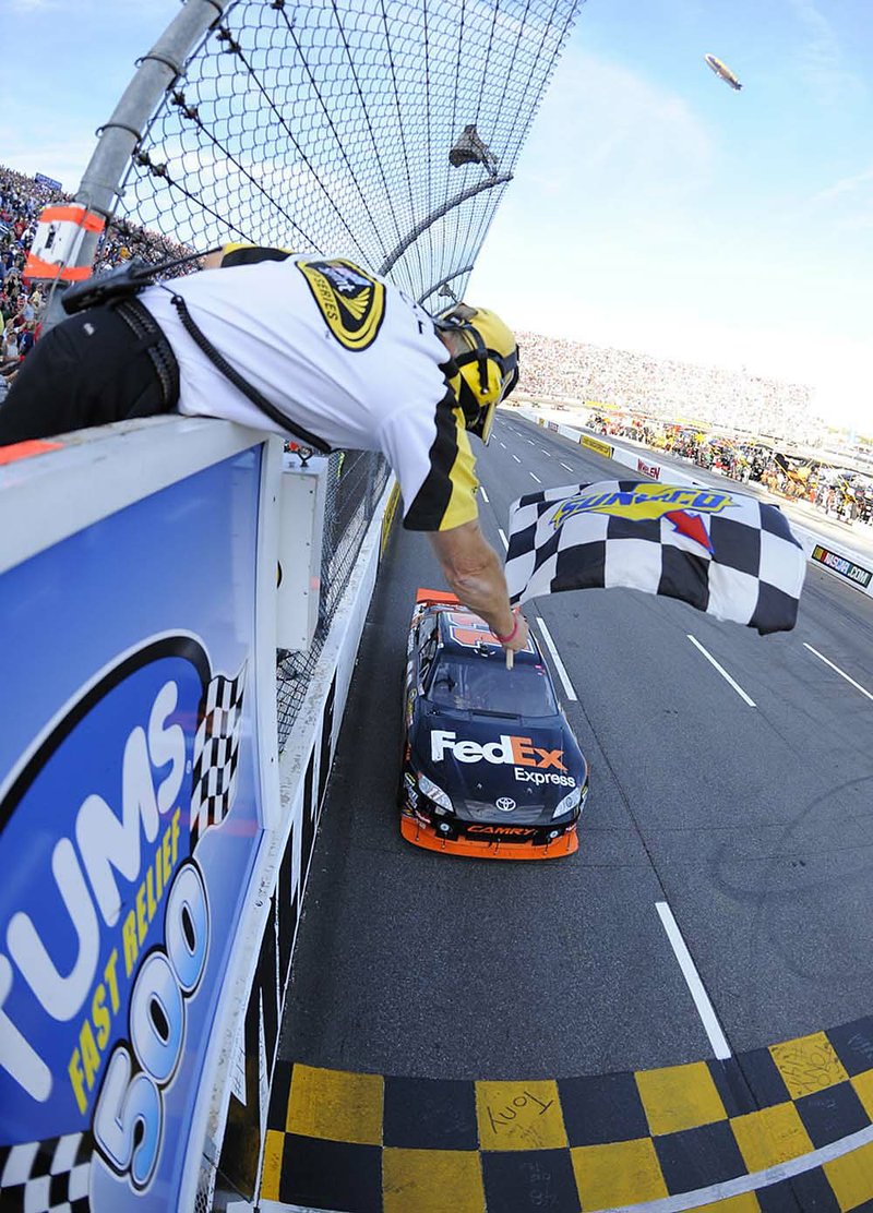 NASCAR Sprint Cup driver Denny Hamlin crosses the finish line to take the checkered flag during Sunday’s race at Martinsville Speedway in Martinsville, Va. 