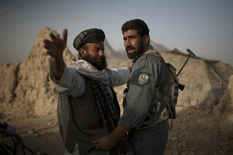An Afghan policeman assigned to U.S. soldiers frisks a villager during a patrol on the outskirts of Kandahar city on Sunday. 