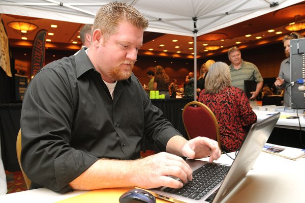 Jason Godsey fills out an employment application Monday at the booth of Farmers Insurance Group during the 2010 Fall Job Fair at the John Q. Hammons Center in Rogers. Godsey has been in sales for more than 20 years and said he was looking for something new after being laid off.