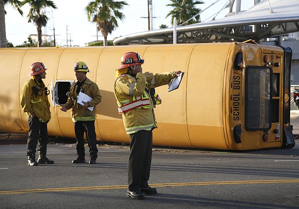 Los Angeles City firefighters investigate the scene of an accident involving a school bus and another vehicle at the intersection of First and Soto Streets in the Boyle Heights area of Los Angeles on Monday, Oct. 25, 2010. A pedestrian was killed and at least 19 people were injured Monday when a black BMW ran a red light and broadsided a school bus, causing it to flip on its side, east of downtown Los Angeles, police said.