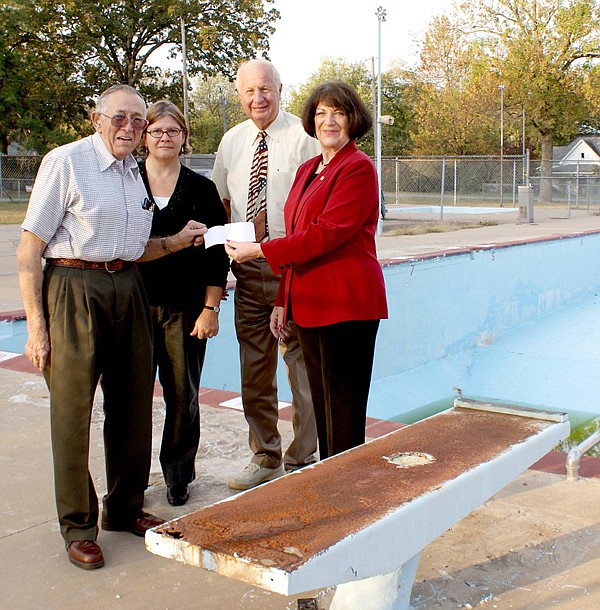 Gravette Mayor Bill Howard, left, and Allyson Ransom, Communications and Resource Efficiency Director, stand in front of a missing diving board at the city pool as they accept a $40,000 check from State Senator Kim Hendren and State Representative Mary Lou Slinkard, a state grant to assist with the pool's repair.