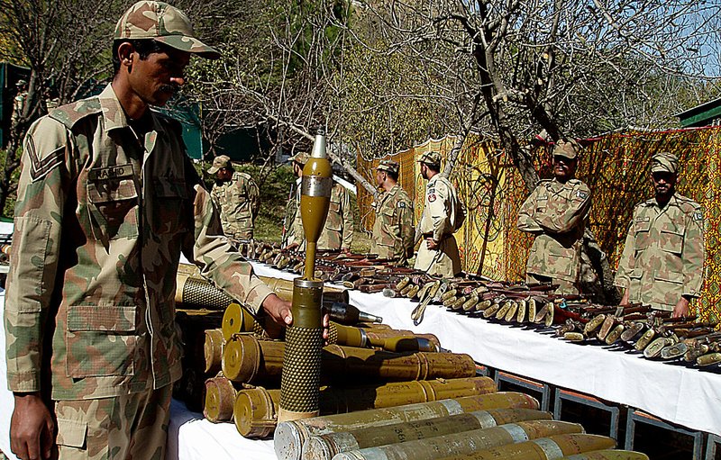 Pakistani soldiers stand near confiscated arms and ammunition Tuesday in Kalaya, Pakistan.