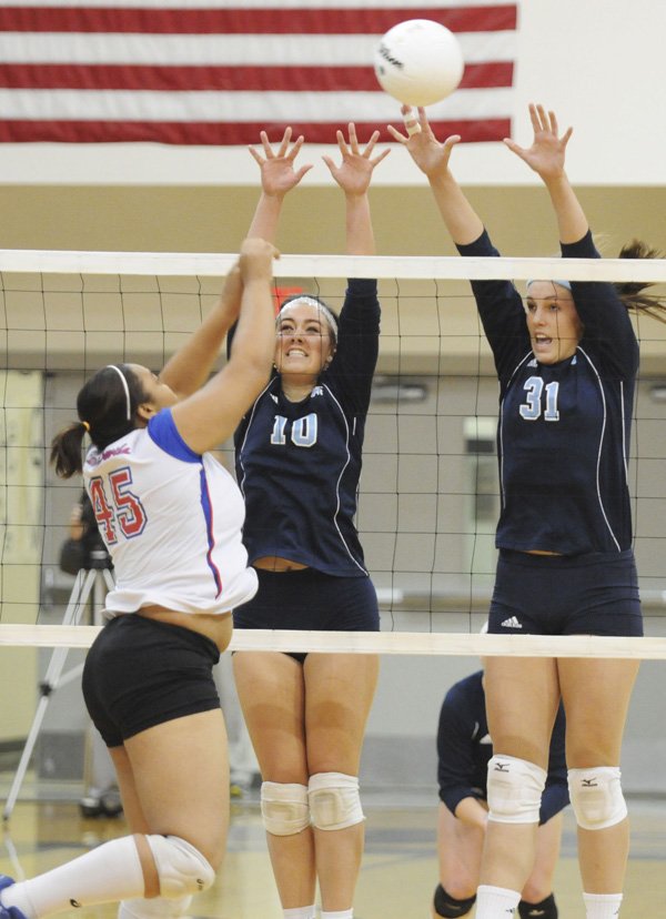 Springdale Har-Ber’s Kellsie Pullen, left, and Katie Huff, right, block a shot by West Memphis’s Jasmine Lewis on Tuesday during the first round of the Class 7A State Volleyball Tournament in Bentonville.