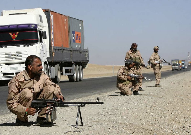 Private security contractors guard a roadway Wednesday as NATO supply trucks roll through the Afghan province of Ghazni southwest of Kabul.

