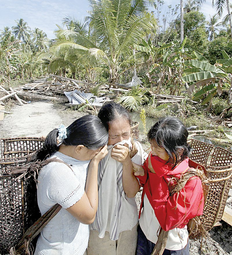 A woman who lost her house and husband in the earthquake-triggered tsunami weeps with her daughters on Pagai island, in Mentawai Islands, Indonesia.