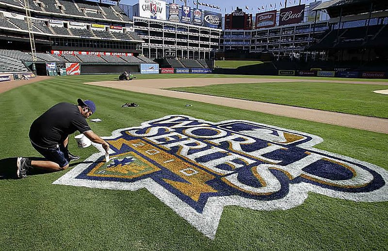 Texas Rangers grounds crew employee Mario Vargas applies the final touches to the World Series logo along the third-base line Thursday at Rangers Ballpark in Arlington, Texas.

