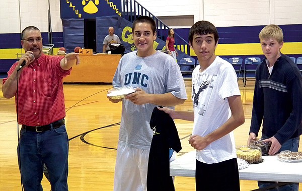 Auctioneer Rob Hopkins took bids on a cream pie with the help of basketball players Taylor Pickup, Bobby Shaw and Evan Owens during the Meet the Bulldogs event on Friday night. The pie auction raised $642 to be used for junior high practice gear, according to coach Donnie Smith. Players were introduced at the event and displayed their skills with scrimmage games and drills.
