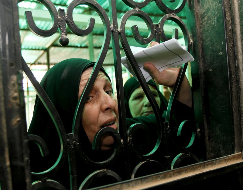 In this June 13, 2010 file photo, an Iraqi widow waits to receive money from a government office in Baghdad, Iraq. Iraq has run out of money to pay for widows' benefits, farm crops and other programs for the poor, the parliament leader on Sunday Nov. 21, 2010, told lawmakers who have collected nearly $180,000 so far this year in one of the world's most oil-rich nations.