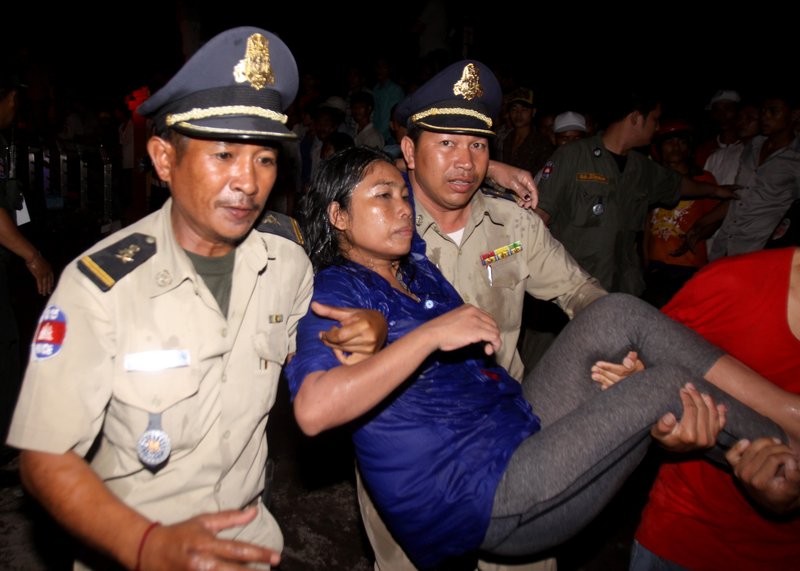 An injured visitor is carried by Cambodian police and another visitor after a stampede onto a bridge at an accident site during the last day of celebrations of the water festival in Phnom Penh, Cambodia, Monday, Nov. 22, 2010. Thousands of people celebrating a water festival on a small island in a Cambodian river stampeded Monday evening, killing many people, a hospital official said. Hundreds more were hurt as the crowd panicked and pushed over the bridge to the mainland. 