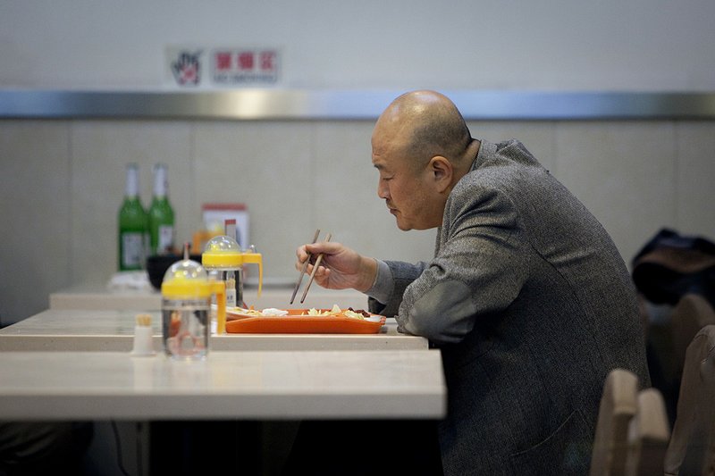 A man eats in a Beijing restaurant on Friday, the day China’s government ordered banks to set aside larger reserves to limit inflation. 