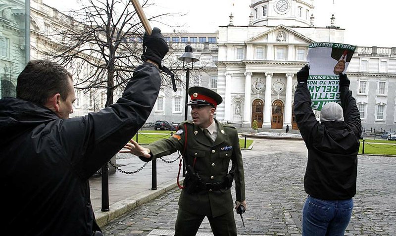 An Irish army military police officer confronts a Sinn Fein protester who broke through the gates at government buildings Monday in Dublin, Ireland.