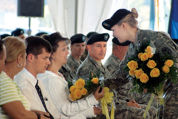  A soldier presents yellow roses to Veronica Collier, widow of Sgt. 1st Class Russell Collier, during a ceremony Tuesday at Fort Hood, Texas, renaming a clinic after the Arkansas National Guard medic.