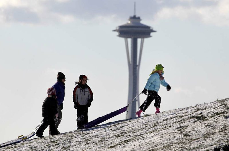Sledders at Seattle’s Gasworks Park walk uphill Tuesday in the shadow of the Space Needle. 