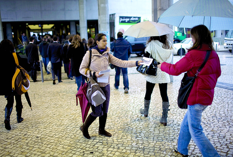 A woman distributes leaflets Friday to commuters arriving in Lisbon promoting a general strike today to protest the Portuguese government’s program to reduce the nation’s deficit. 