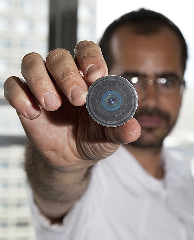 New York University arts professor Wafaa Bilal holds the prototype of a camera he had implanted in the back of his head.

