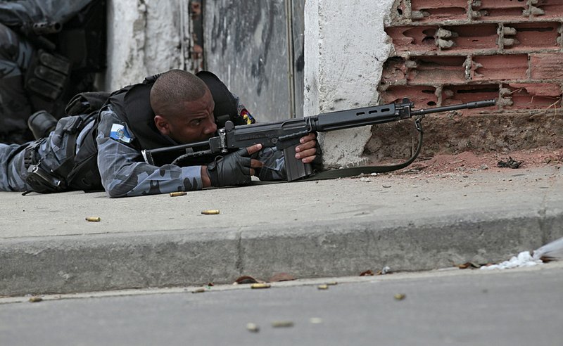 A Brazilian policeman holds his position Friday during an operation against drug traffickers in a slum complex in Rio de Janeiro. Police and military forces have gang members trapped inside the Alemao slum and another complex of shantytowns, and, while officials weren’t commenting, an invasion seemed imminent.
