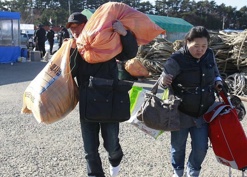 People carry what they can as they try to get on a boat to leave the embattled Yeonpyeong island near South Korea’s border with North Korea. 