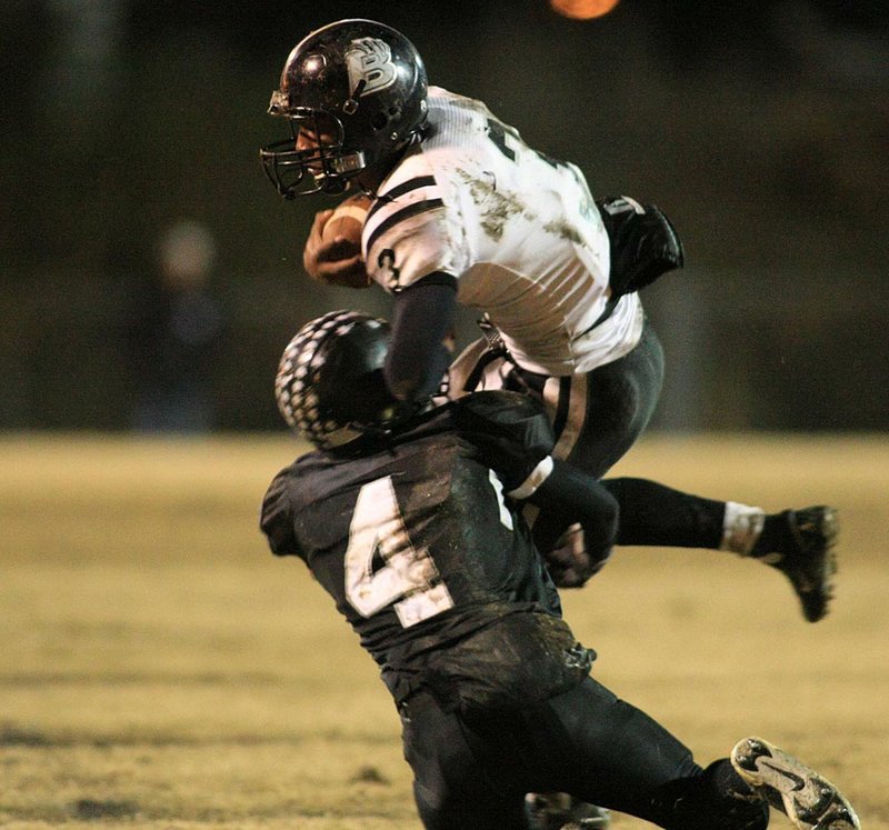 Bearden’s Defonta Lowe (top) tries to escape a tackle by Bigelow’s Justin Southerland in the first quarter of a Class 2A playoff game Friday night in Bigelow. Bearden advanced with a 21-14 victory. 