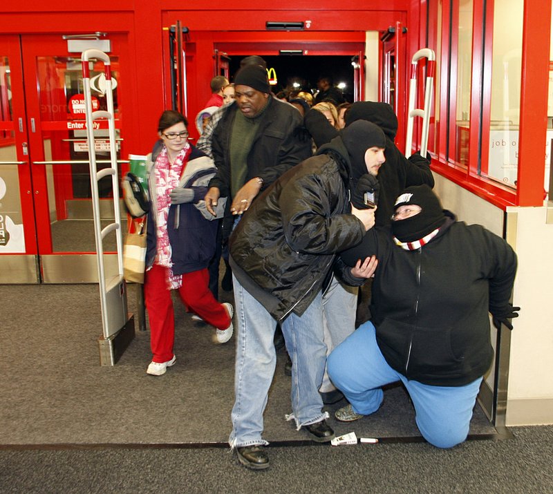 Jennifer Johnston of Jacksonville is helped up after stumbling when she entered the Target in North Little Rock after the store opened its doors at 4 a.m. Friday. 