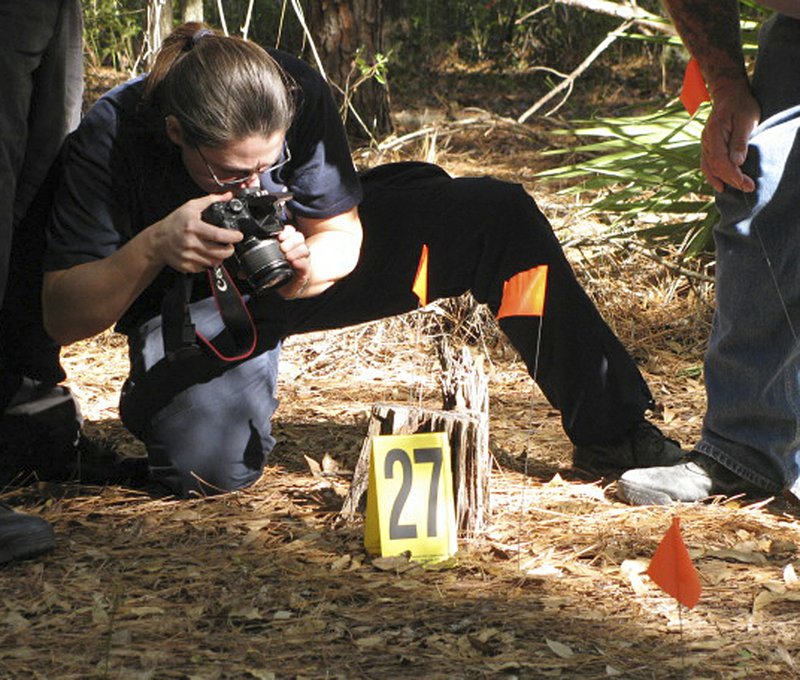 Diane Robinson of the American Humane Association demonstrates forensic techniques at a staged crime scene during a veterinary forensics seminar at the University of Florida in Gainesville earlier this month.

