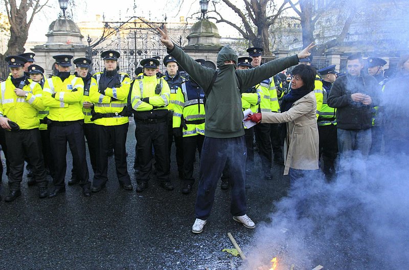 A protester stands in front of a line of police Saturday outside Leinster House in Dublin.

