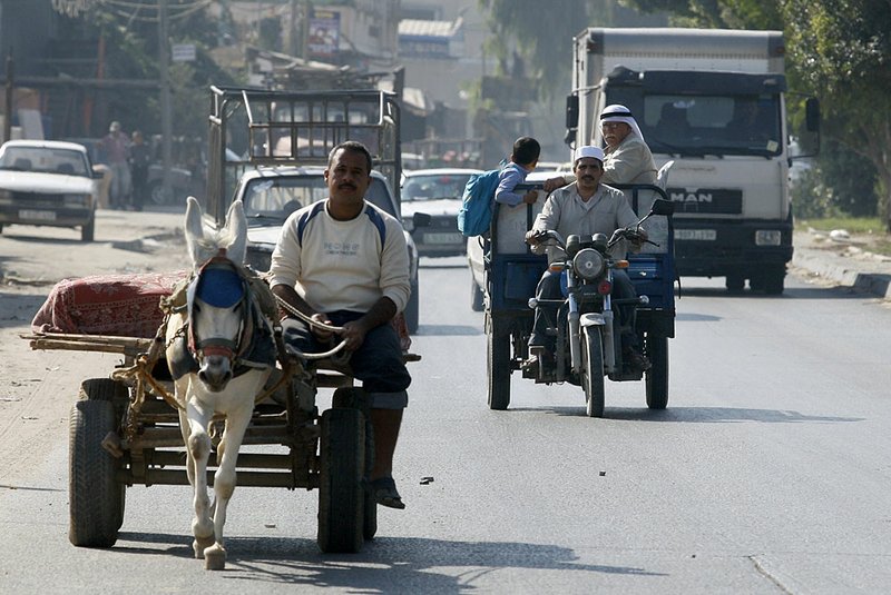 Palestinians ride a tuk-tuk behind a donkey cart Thursday in Gaza City.

