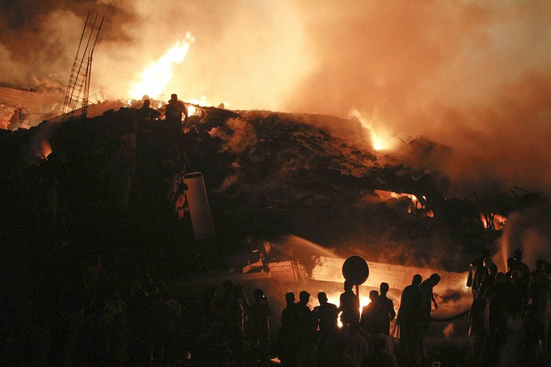  Pakistani volunteers and firefighters struggle to extinguish a fire at the site of a plane crash in Karachi, Pakistan on Sunday, Nov. 28, 2010. A cargo plane crashed into a housing complex in Pakistan's largest city soon after takeoff Sunday, setting off a huge blaze. The aircraft had eight crew on board, the civil aviation authority said. 