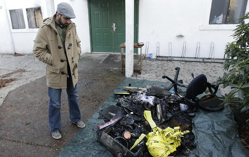 Ahson Saeed, who is a longtime worshipper at the Salman Al-Farisi Islamic Center, stands over a pile of burned debris pulled from the center Sunday in Corvallis, Ore. 