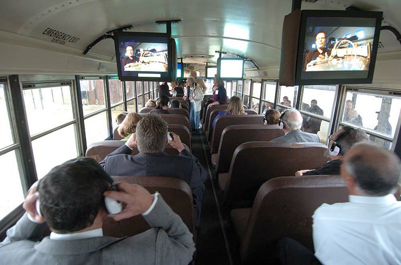 Attendees of a press conference ride a school bus equipped with ceiling-mounted computers Monday as officials demonstrated a new initiative to help educate students while they travel along rural roads to and from school. 