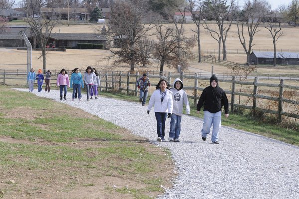 Tyson Elementary School fifth-graders walk along a trail Wednesday on the playground at the school in Springdale. The trail was built with a grant and seven Springdale elementary schools have or will build trails. The trail at Tyson will be paved sometime next spring.
