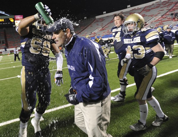 Shiloh Christian senior lineman Troy Goss, left, celebrates with coach Josh Floyd on Friday after the Saints defeated Pulaski Academy 61-40 in the Class 4A State Championship Game in War Memorial Stadium in Little Rock.
