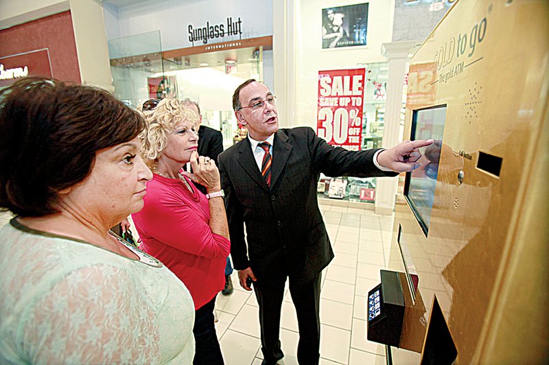 Thomas Geissler, chief executive officer of Ex Oriente Lux, shows Gloria Brooks and Barbara Abrams, both of Fort Lauderdale, Fla., how to use the Gold To Go machine Friday in the Town Center Mall in Boca Raton, Fla. 