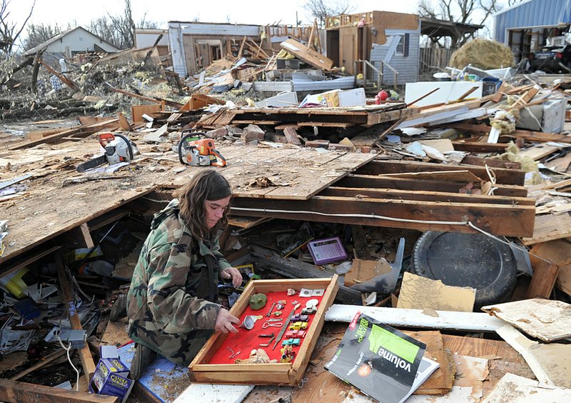 Naomi Vaughn helps recover items from neighbor Chris Sisemore’s Cincinnati home after a Friday morning tornado ripped through the Washington County town, killing three people. 