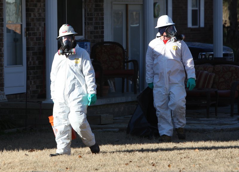 Workers with United States Environmental Services LLC don protective gear as they pick up dead birds along Leewood Cove on Sunday morning in Beebe.