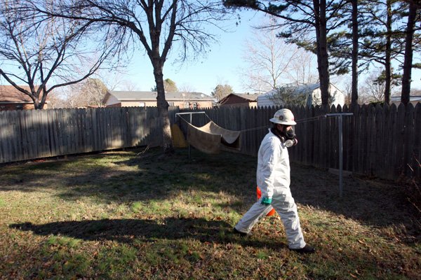 Workers with United States Environmental Services LLC don protective gear as they pick up dead birds in the back yard of a home along Leewood Cove Sunday morning in Beebe.
