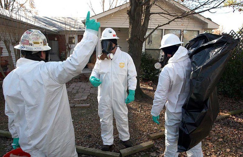 Workers with U.S. Environmental Services LLC don protective gear Sunday as they remove dead birds from the backyard of a home along Leewood Cove in Beebe.

