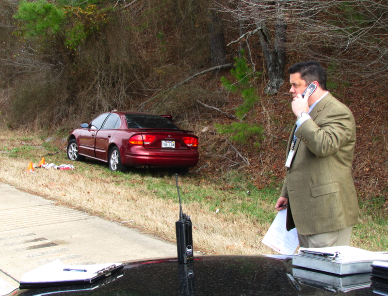 A Little Rock Police Department detective works at the scene where two injured men pulled off called for help on Interstate 430. The men had been shot during a robbery try at a nearby grocery store, police said.