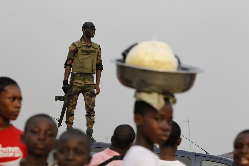 A member of the security forces stands guard as people gather for a rally by youth leader Charles Ble Goude in support of Laurent Gbagbo, who recently named Goude to his cabinet, in the Koumassi neighborhood of Abidjan, Ivory Coast, Wednesday, Jan. 5, 2011. While the United Nations and other world powers recognize rival Alassane Ouattara as the winner of November presidential elections, Gbagbo has refused to step down for more than a month after the presidential runoff vote. The 15-nation regional bloc ECOWAS (The Economic Community Of West African States) has threatened to remove the incumbent leader if ongoing negotiations fail.