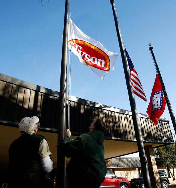 Maintenance workers Wayne Watson (left) and Denny Birdsong lower the Tyson Foods Inc. flag Thursday outside company headquarters in Springdale to honor Don Tyson, the former chairman and chief executive officer and son of founder John W. Tyson.
