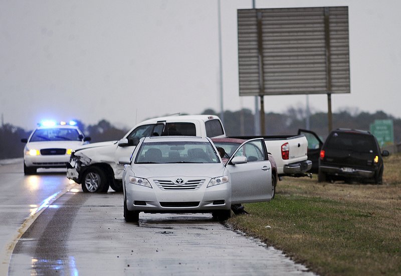 Vehicles sit on the edge of a road and in the grass after a multivehicle crash Sunday in wet, icy weather on Interstate 55 in Jackson, Miss. 