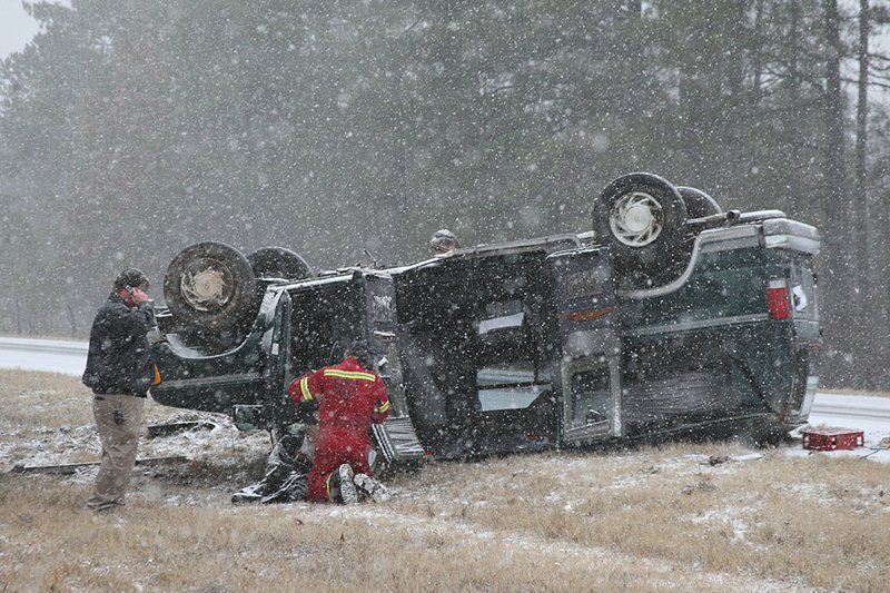 Emergency workers tend to an injured woman in a sport utility vehicle that overturned 15 miles north of Pine Bluff on an icy stretch of Interstate 530 Sunday afternoon. 
