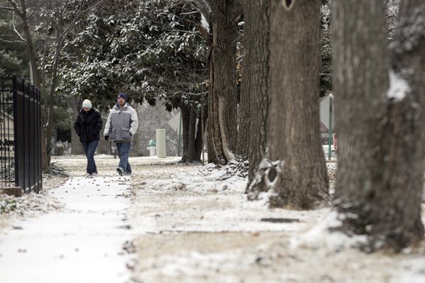 Sharon Gordon, left, and Luke Baker take a walk Monday along Fourth Street in Rogers. The pair decided to go for a walk to look at the snow which fell overnight with most of it melting away during the day.