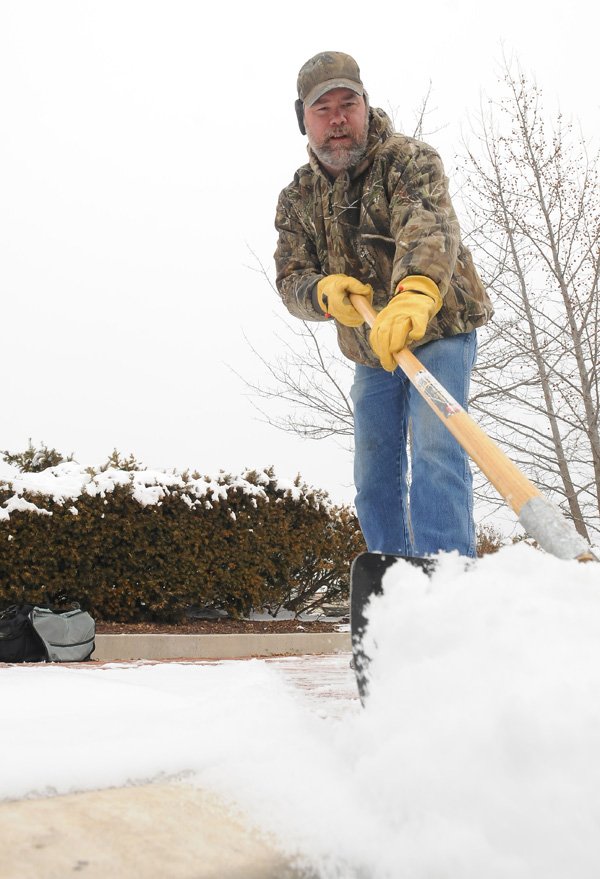 Andy Hoover shovels some of Thursday’s snow from the sidewalks Friday in front of Midtown Center in Bentonville. More light snow is possible Sunday through Tuesday for the area, according to the National Weather Service.
