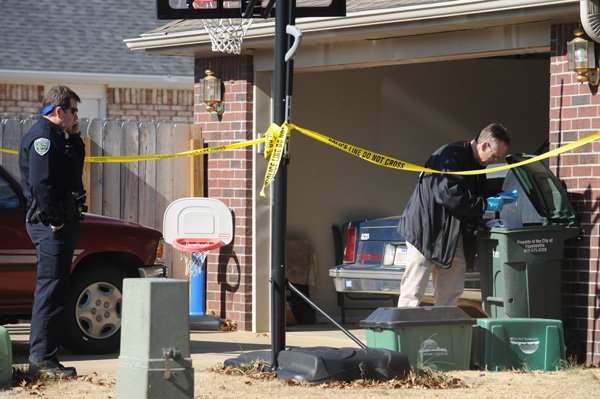 John Brooks, crime scene investigator for the Fayetteville Police Department, right, collects evidence near the rear entrance of a house at 5657 W. Reliance St. in Fayetteville Wednesday, Jan. 26, 2011, after police responded to a report of a shooting at the residence.